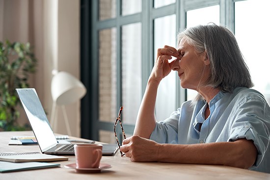 A person holding her nose and looking at a computer

Description automatically generated